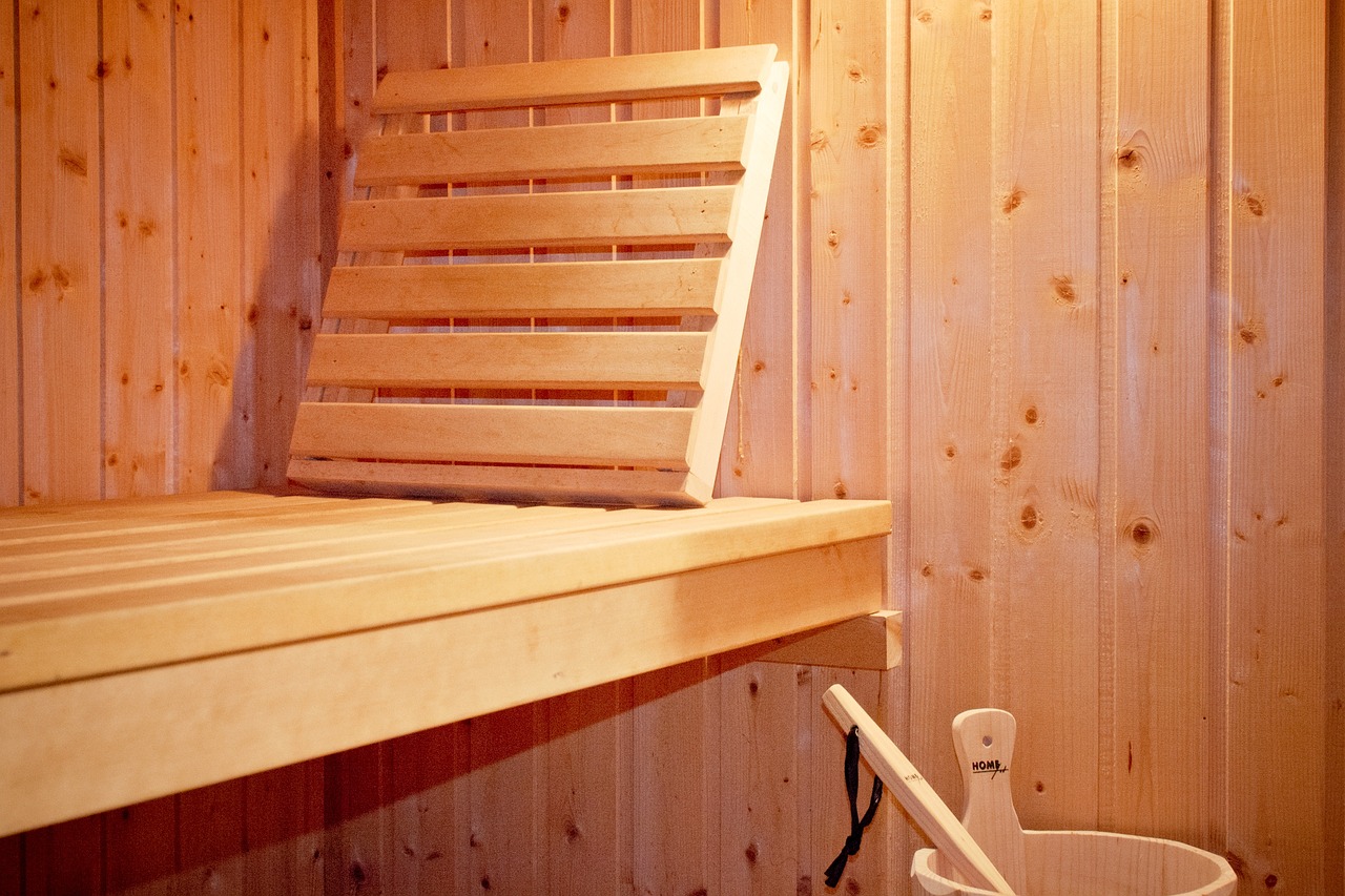 Foto einer Liegebank einer Sauna, danaben steht ein Eimer.